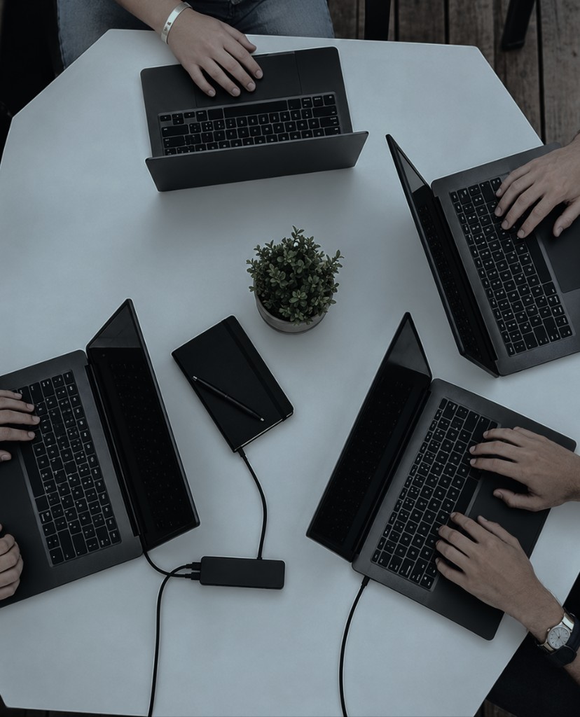 Team members collaborating with laptops around a table